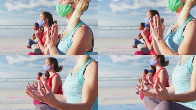 一群女性朋友戴着口罩在海滩上冥想