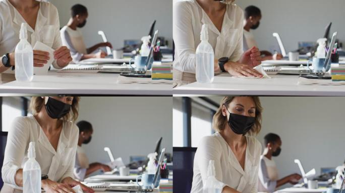 两位不同的女同事戴着口罩，在办公室的办公桌上消毒