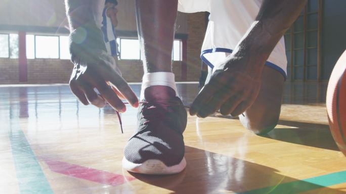 非裔美国男篮球运动员系鞋与球队在背景
