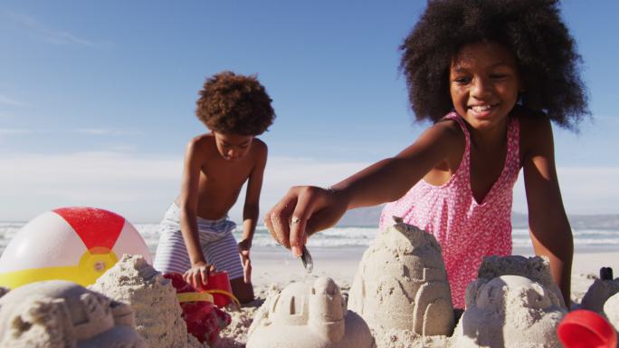 非洲裔美国兄妹在沙滩上玩沙子