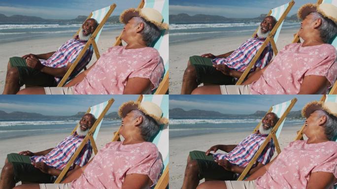 老非洲裔美国夫妇坐在沙滩上的日光浴床上微笑