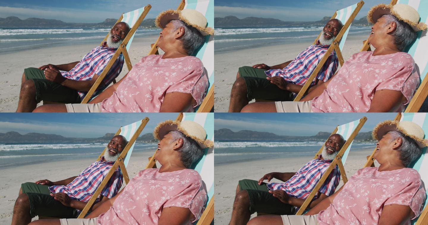 老非洲裔美国夫妇坐在沙滩上的日光浴床上微笑