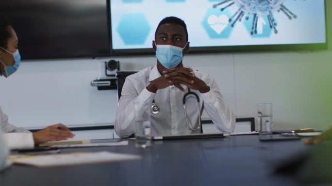 非裔美国男医生戴着口罩在会议室做报告