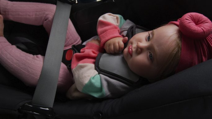 一位白人母亲在车里的安全座椅上亲吻她的孩子