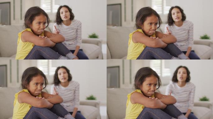 愤怒的西班牙裔母亲责备她坐在沙发上的年轻女儿