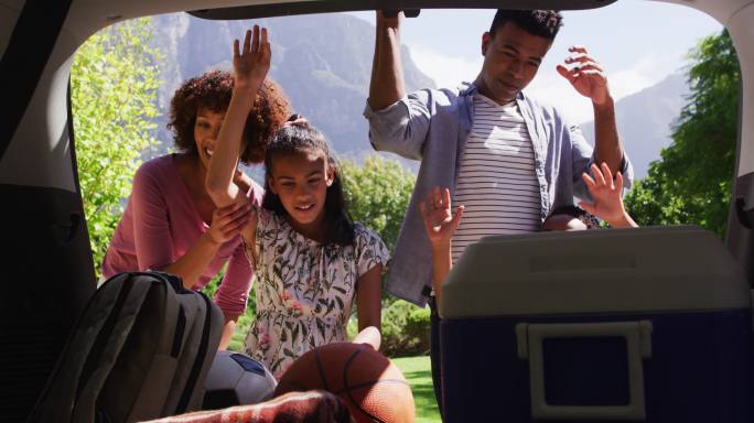 快乐的非裔美国父母，儿子和女儿，打开汽车后备箱野餐用品