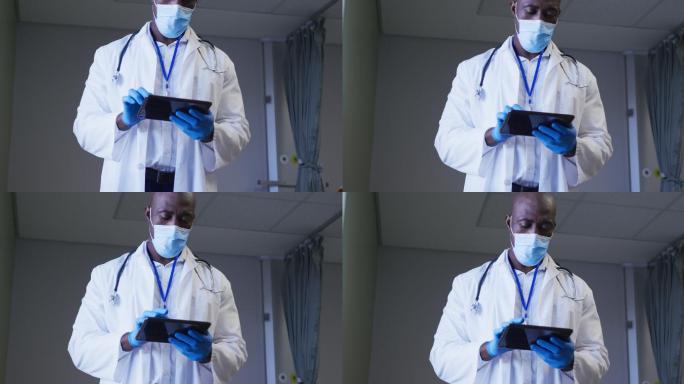 非裔美国男医生戴着口罩在医院病房使用数码平板电脑