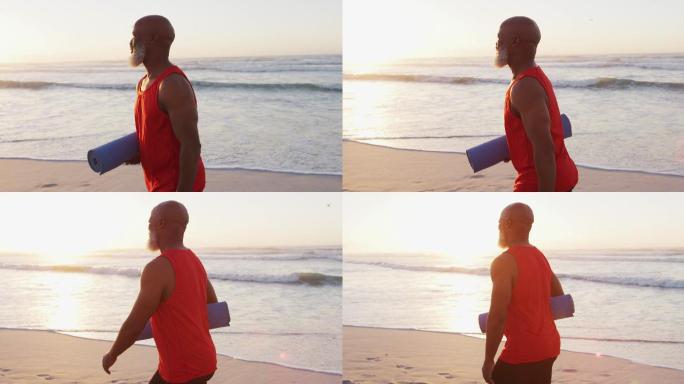 一名非洲裔美国老人在沙滩上用瑜伽垫散步