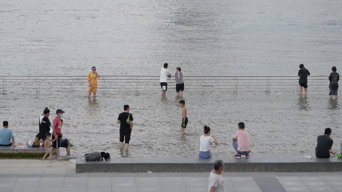 夏天消暑纳凉水边江滩边上玩水的人群