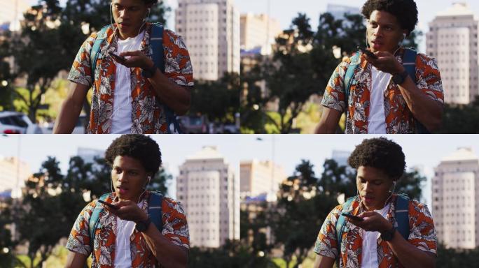 非裔美国人，戴着耳机，在街上用智能手机说话
