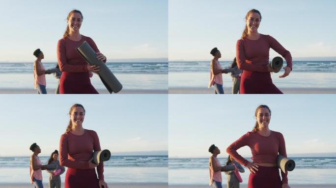 一群不同类型的女性朋友在沙滩上拿着瑜伽垫