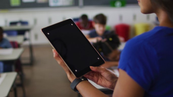 混血儿教师腹部使用平板电脑，屏幕上有复制空间，背景是孩子