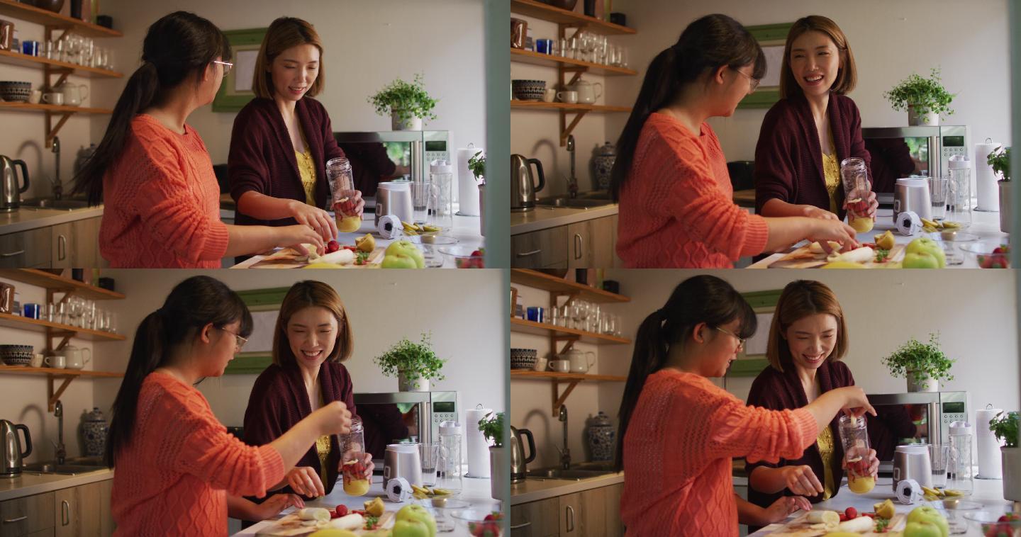 亚洲母亲和女儿在厨房准备健康饮料微笑