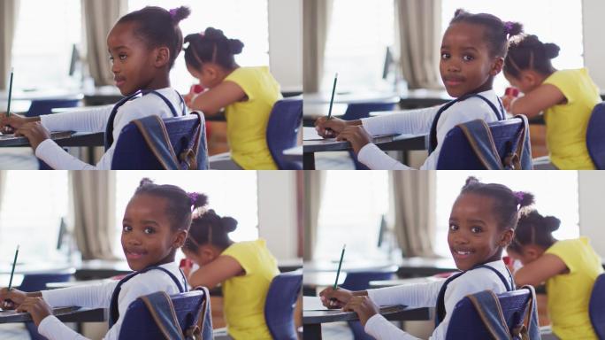 快乐的非裔美国女学生的肖像坐在教室里，做笔记，看着相机