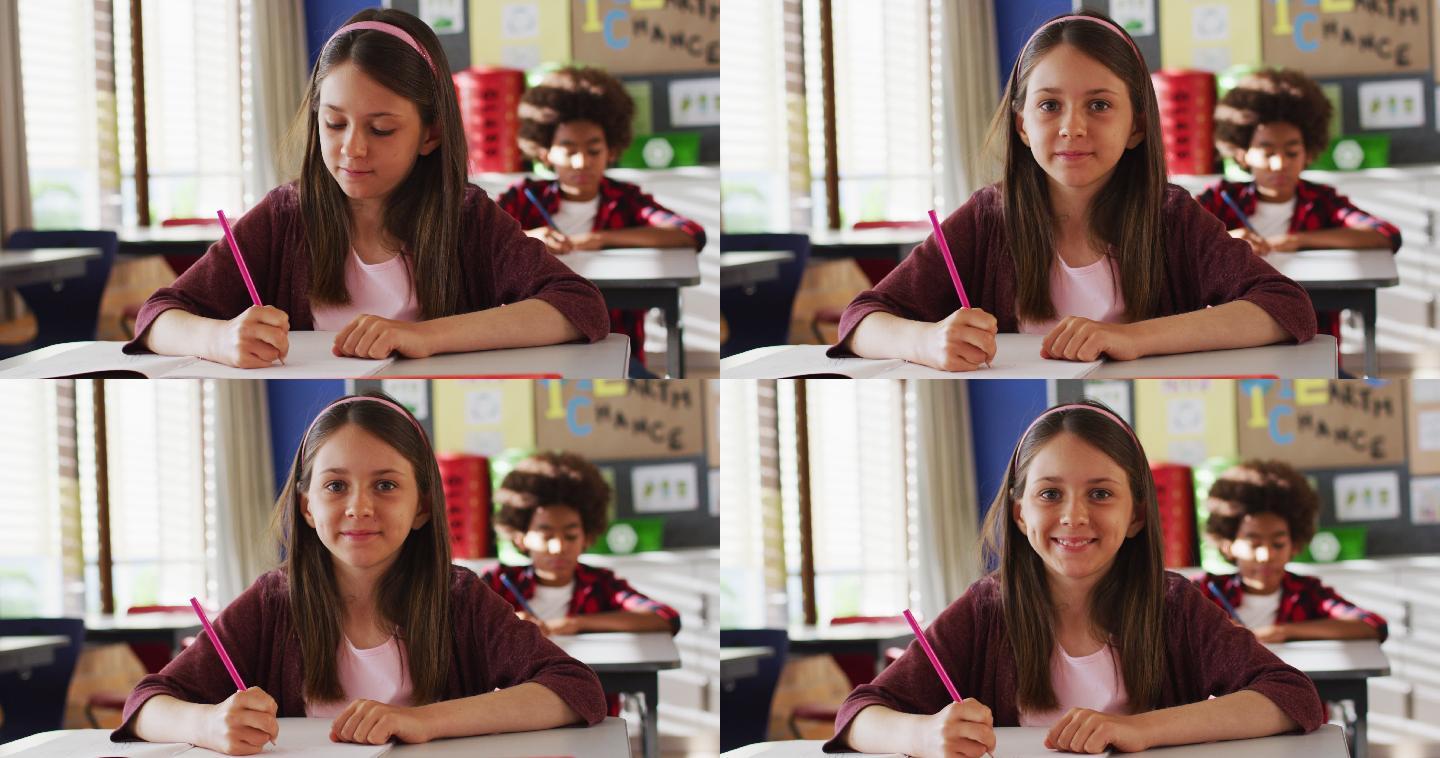 白人女学生的肖像坐在课堂上，做笔记，看着相机