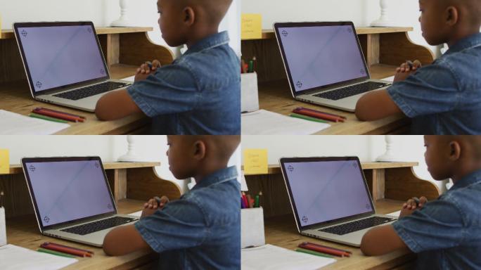 一个非裔美国男孩在网上学校的课堂上使用笔记本电脑，屏幕上有拷贝空间