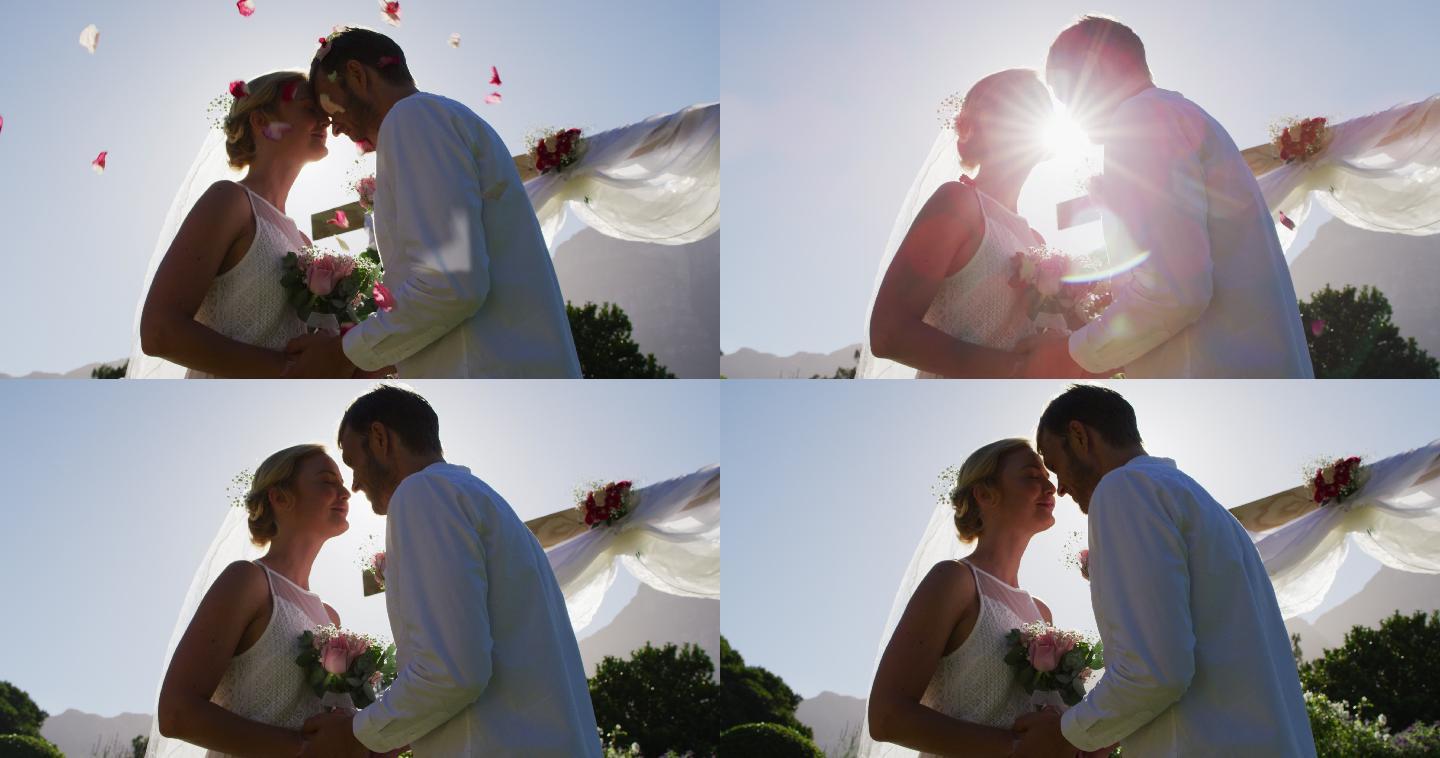 幸福的白人新婚夫妇，站在户外的圣坛前，触着头