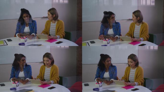 不同的商业女性同事在工作中使用电子平板电脑进行讨论
