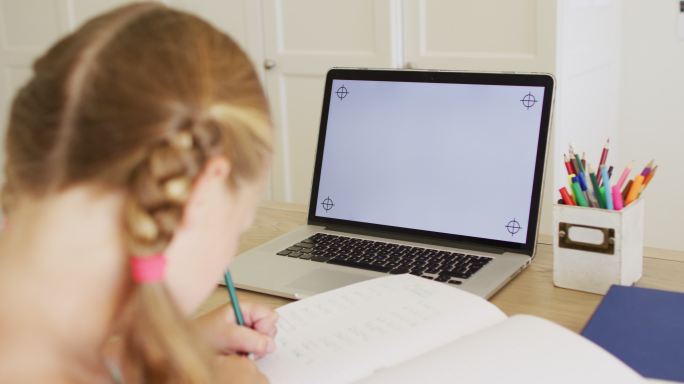 白人女孩在家里做作业的时候用笔记本电脑打视频电话