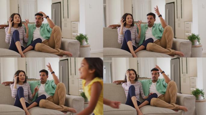 愤怒的西班牙裔父母坐在沙发上看着跳舞的女儿争吵