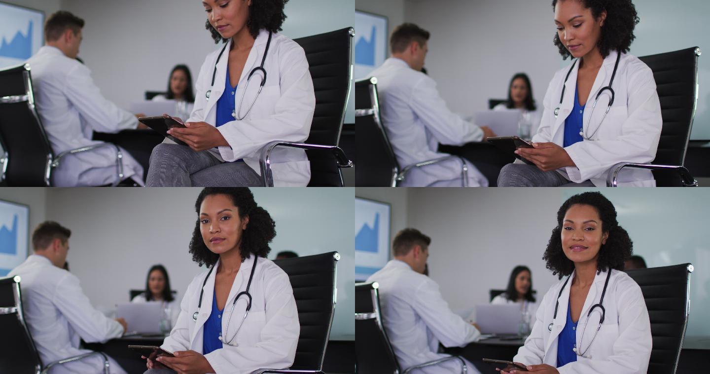 混血儿女医生坐在会议室里，拿着平板看着摄像机微笑