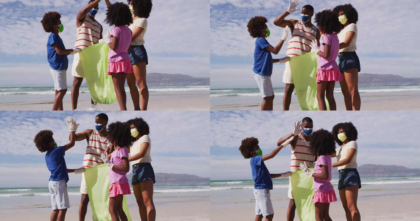 非裔美国父母带着两个戴口罩的孩子在海滩上捡拾垃圾