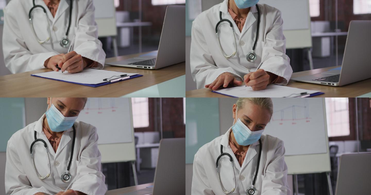 白人女医生戴着口罩坐在会议室的桌子前做笔记