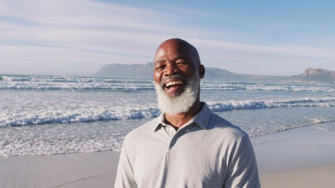 一位年长的非洲裔美国人在海滩上微笑