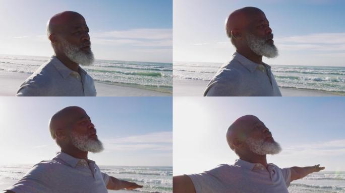 一位年长的非裔美国人站在海滩上，闭上眼睛欣赏着眼前的景色
