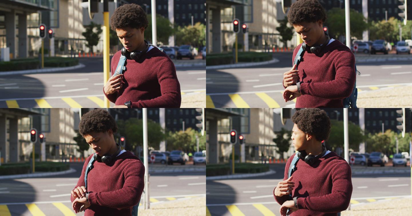 非洲裔美国人在城市中检查智能手表，戴着耳机和背包在街上等待