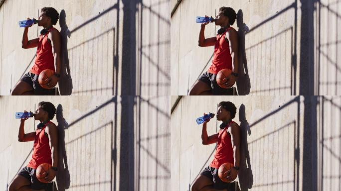 健康的非洲裔美国人在城市运动，休息，喝水，打篮球