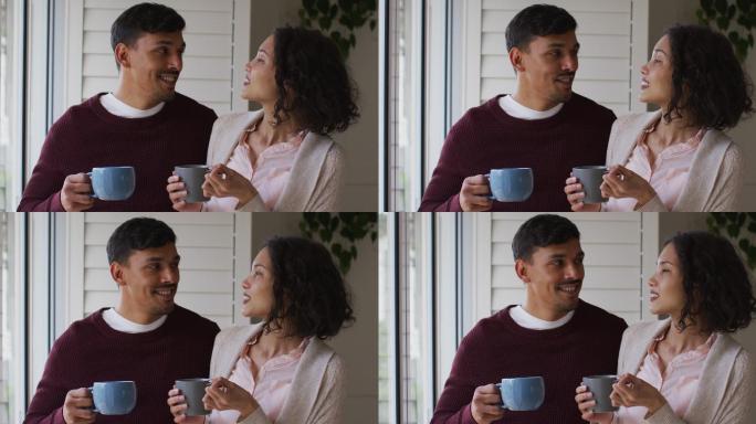 一对浪漫的西班牙夫妇站在窗前，喝着咖啡，拥抱在一起