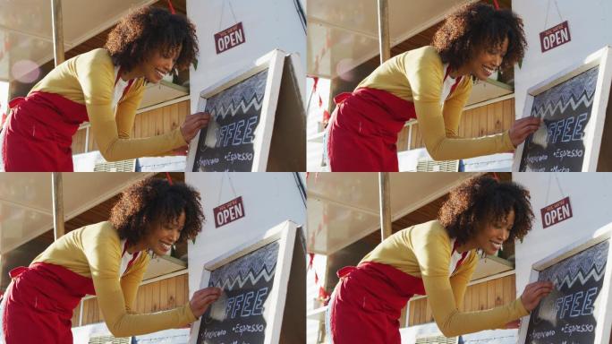 非裔美国妇女穿着围裙在餐车的菜单板上写字