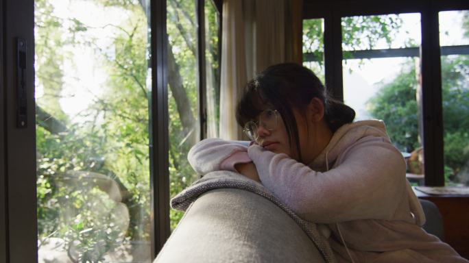 亚洲女孩看着窗外，躺在沙发上