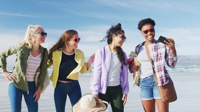 一群快乐的女性朋友在沙滩上用智能手机自拍