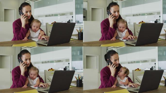 一位白人母亲抱着她的孩子在家里用智能手机和笔记本电脑聊天