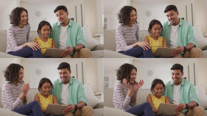 幸福的西班牙父母和女儿坐在沙发上用笔记本电脑