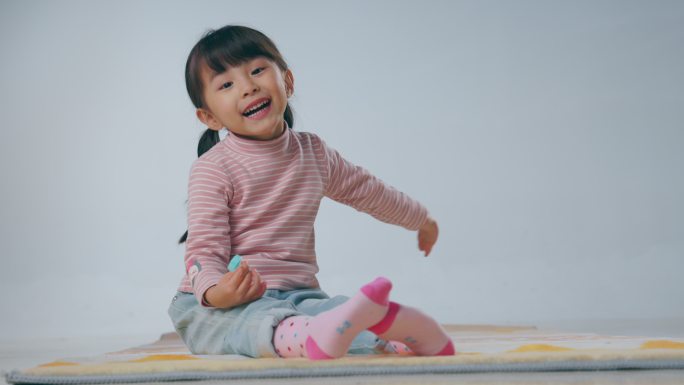 快乐的小女孩坐在地毯上吃棒棒糖