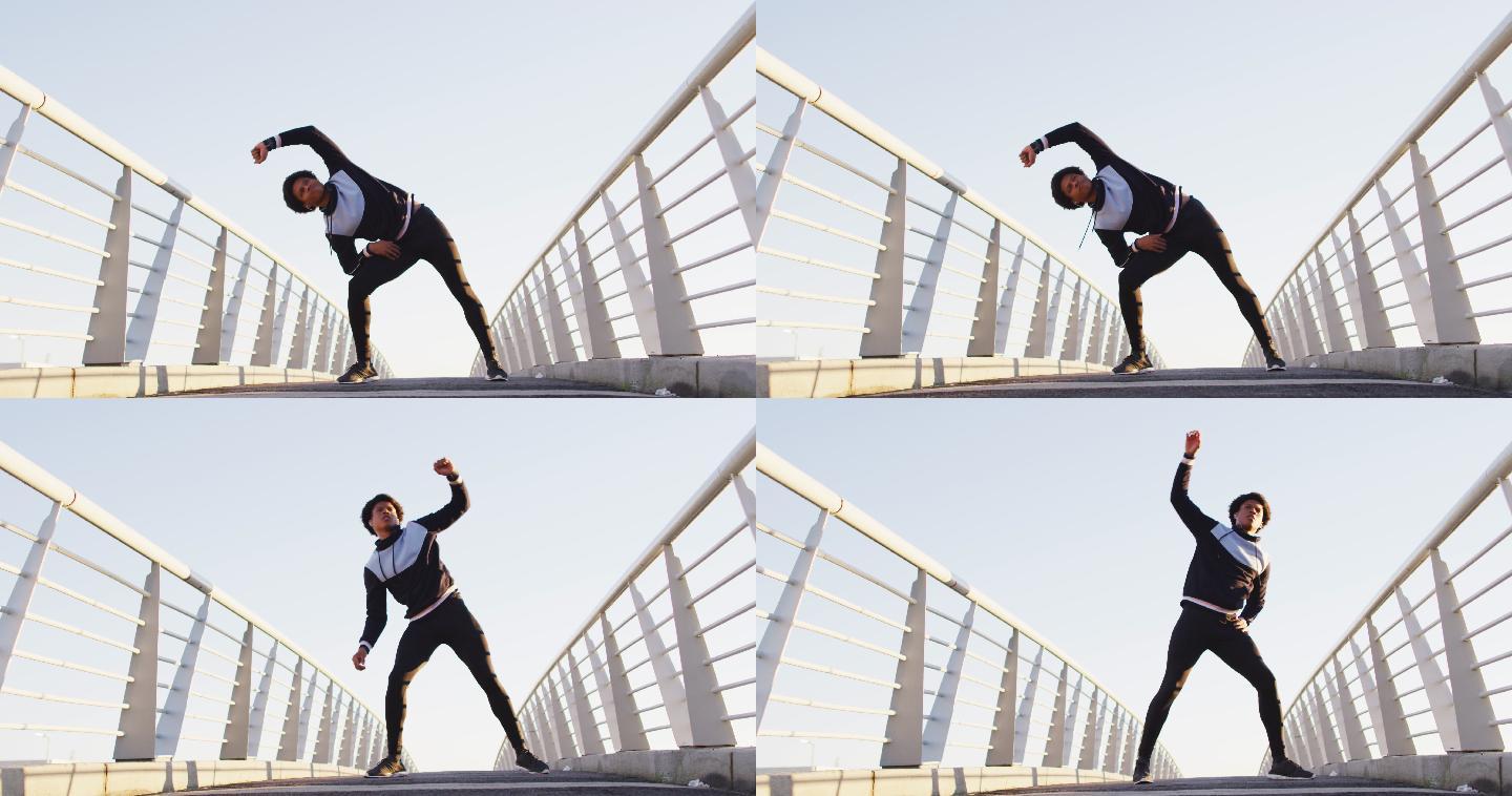 非裔美国男子在户外运动，站在人行天桥上，腰部以上伸展