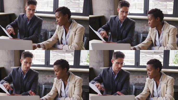 不同的男性和女性商业同事坐在咖啡馆聊天，看着笔记本电脑和文件