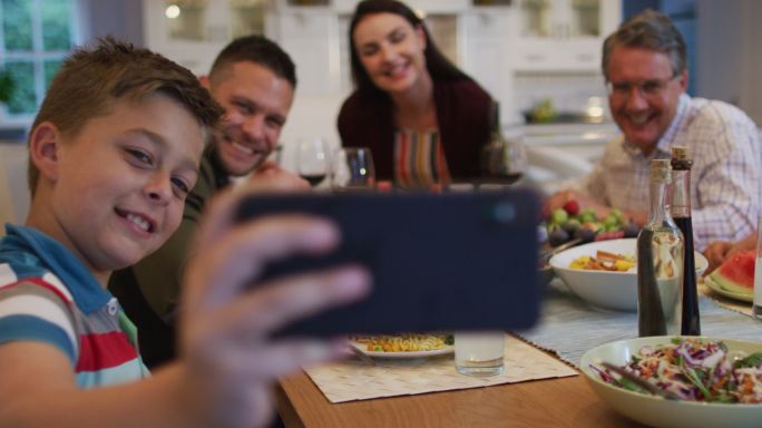 快乐的白种人孙子与父母和祖父在餐桌上自拍在家庭用餐
