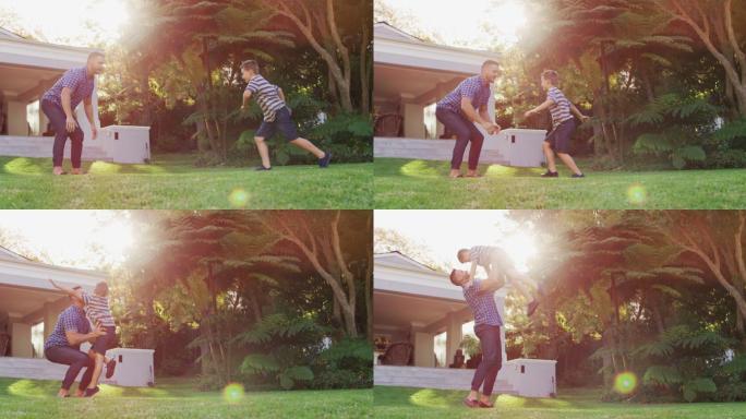 快乐的白种人儿子在阳光花园的父亲的怀抱里奔跑跳跃