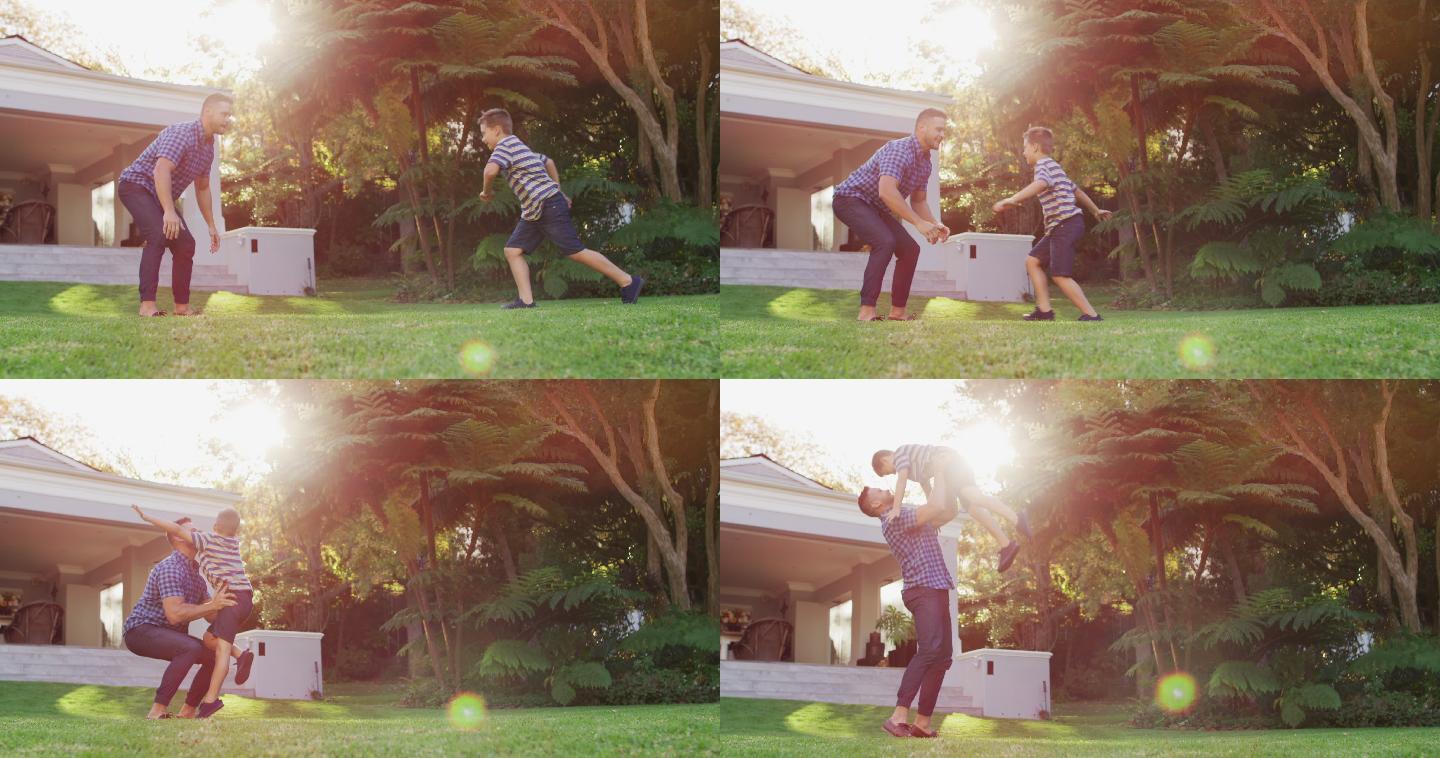快乐的白种人儿子在阳光花园的父亲的怀抱里奔跑跳跃