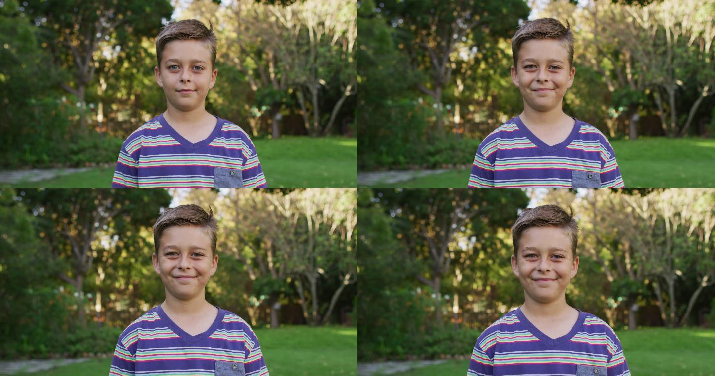 快乐的白人男孩的肖像站在花园对相机微笑