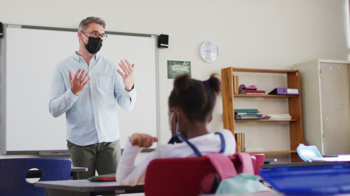 戴着口罩的白人男教师在学校上课