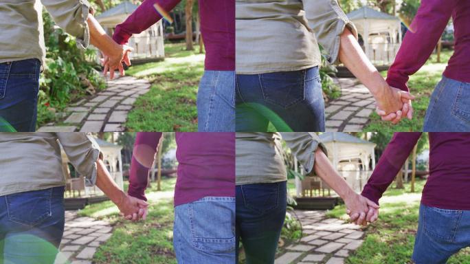 后视图中段老年白人夫妇手牵着手，在花园里散步