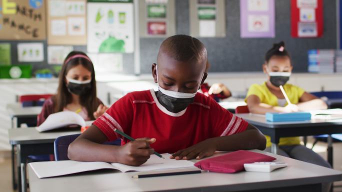 非裔美国男孩在学校上课时戴着口罩