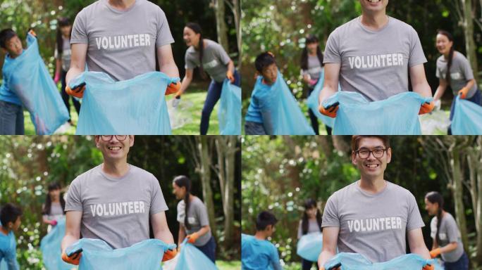 微笑的亚洲男子穿着志愿者t恤，手拿垃圾袋收集塑料垃圾