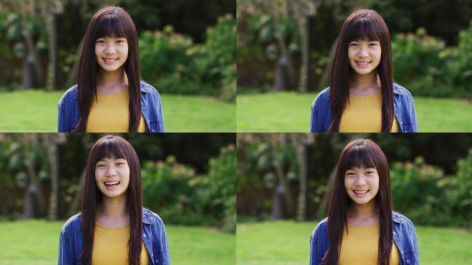 快乐的亚洲少女的肖像看着照相机微笑和大笑在花园