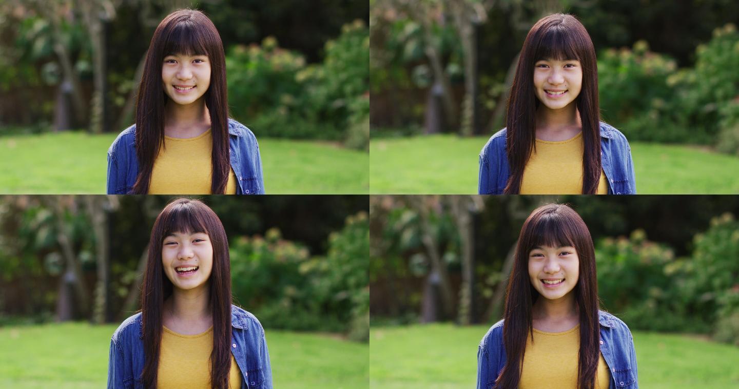 快乐的亚洲少女的肖像看着照相机微笑和大笑在花园